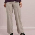 Person wearing light gray wide-leg pants with a dark burgundy top and brown sneakers with white soles, shown from the waist down.