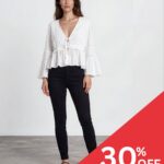 Model wearing a white V-neck peasant blouse and black skinny jeans stands against a plain light background with a red 30% OFF promotion banner in the corner.