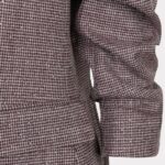 Close-up of a maroon houndstooth blazer sleeve with cuff and pocket seam.