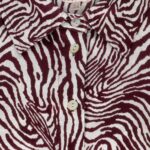Close-up of a burgundy-and-white zebra-print button-down shirt, showing the collar and light-colored buttons.