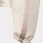 Beige joggers with a patterned side stripe and elastic cuffs at the ankle.