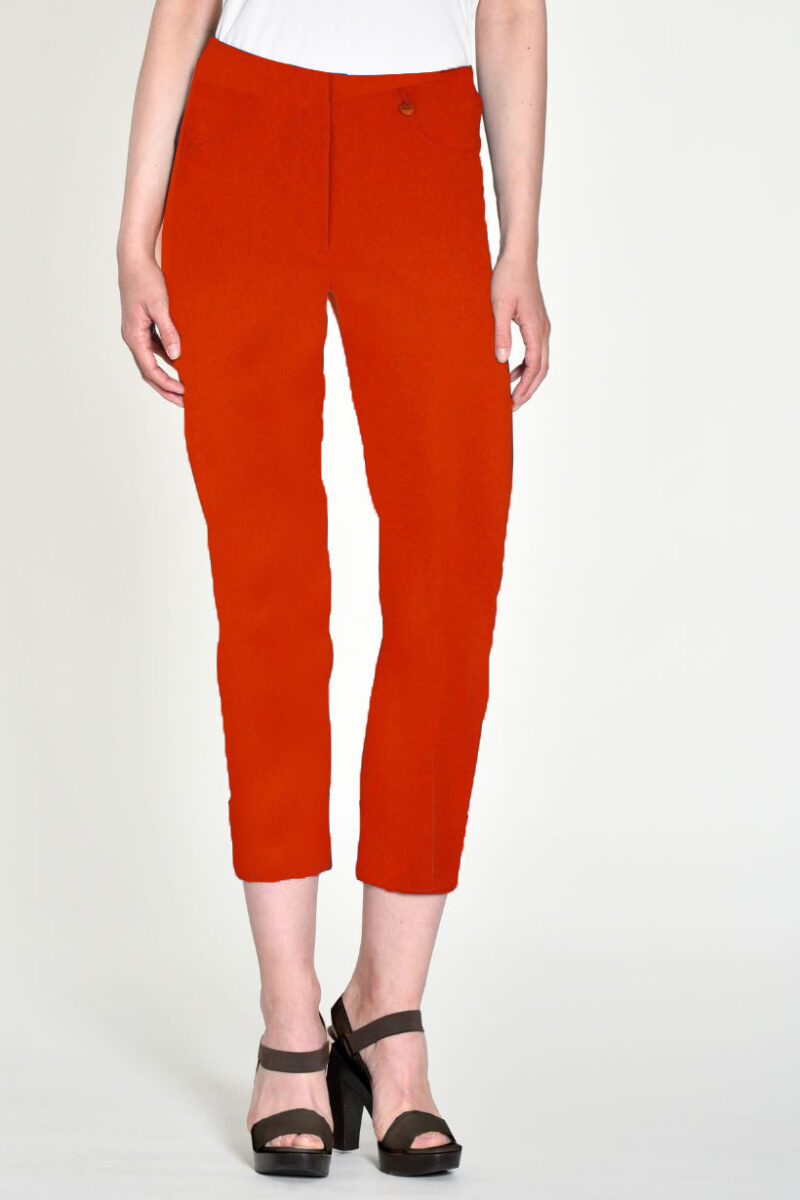 Orange-red cropped pants worn by a model, paired with a white top and brown platform sandals.