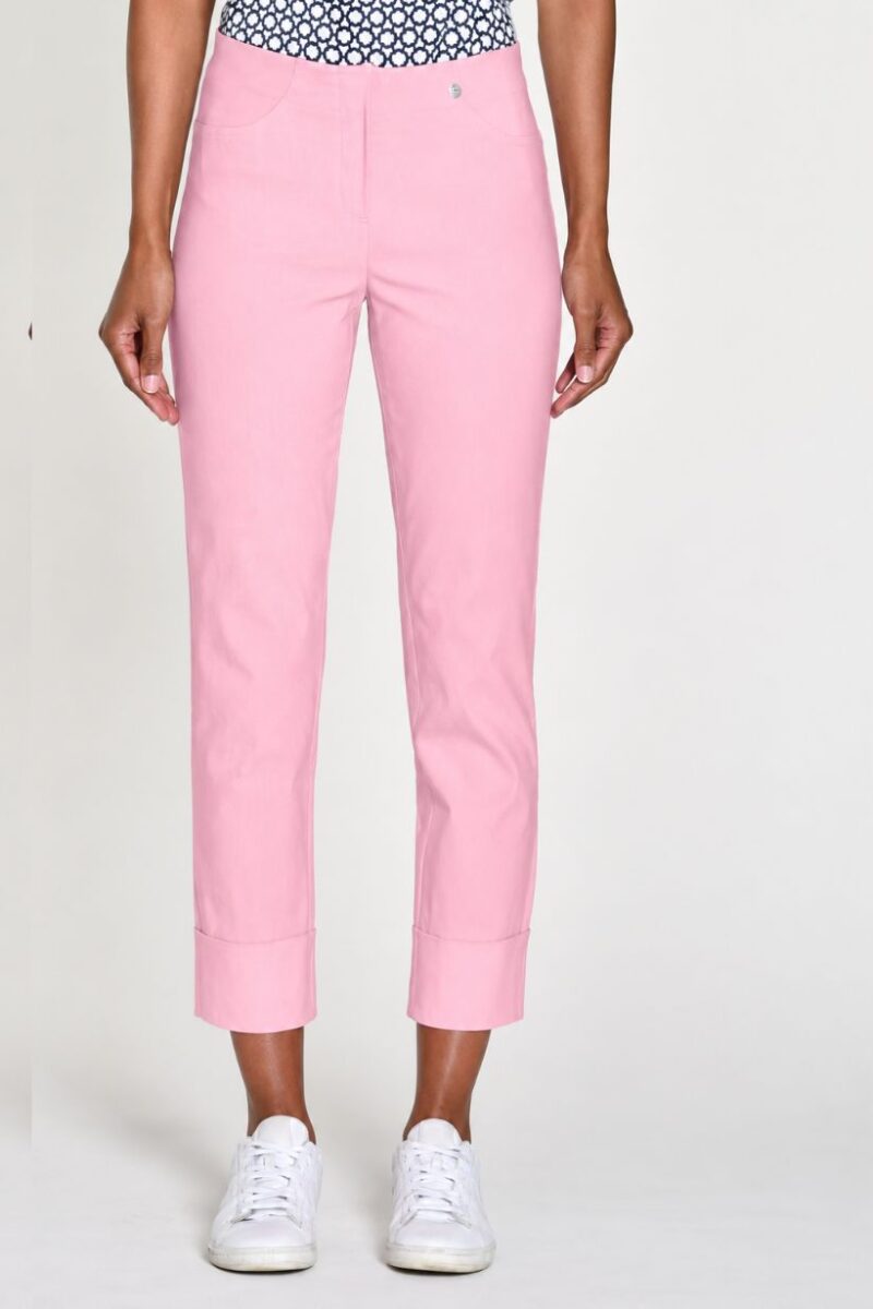 Light pink cropped trousers with wide cuffs worn by a model paired with white sneakers, full-length view.