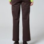 Back view of a person wearing brown wide-leg pants, black platform shoes, and a bright lime-green knit top.